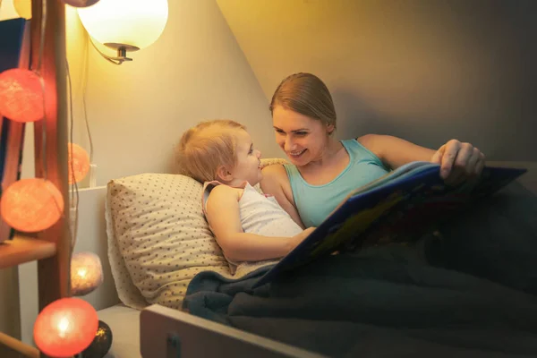 Mother reading fairy tail book to her child in the evening befor — 스톡 사진