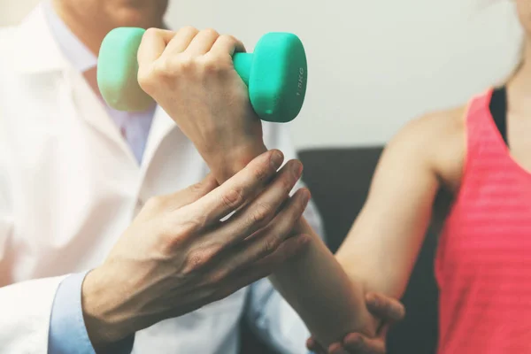 Fysiotherapie - fysiotherapeut helpen vrouwelijke patiënt om te herstellen van handletsel thuis. halter oefeningen — Stockfoto