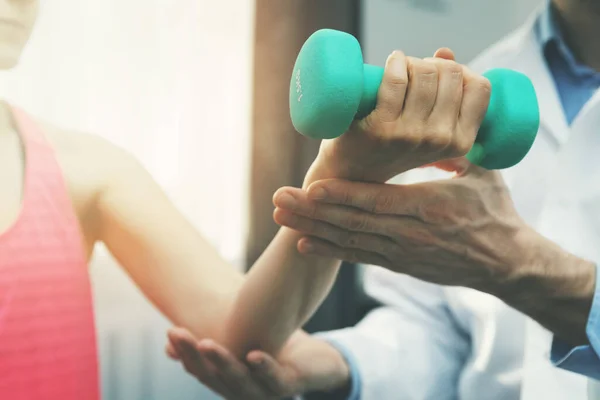 Fysiotherapie - fysiotherapeut helpen vrouwelijke patiënt om te herstellen van handletsel thuis. halter oefeningen — Stockfoto