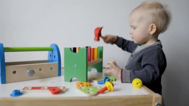 Küçük çocuk evde oyuncak alet kutusuyla oynuyor.