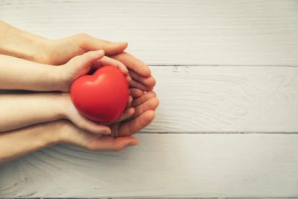 Rotes Herz Kinder Und Erwachsenenhänden Auf Weißem Holzgrund Gesundheitskonzept Organspende — Stockfoto