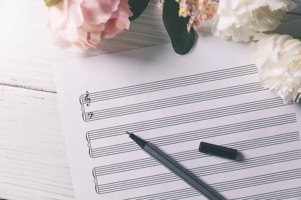 Hoja Notas Música Blanco Con Flores Pluma Sobre Mesa Madera —  Fotos de Stock