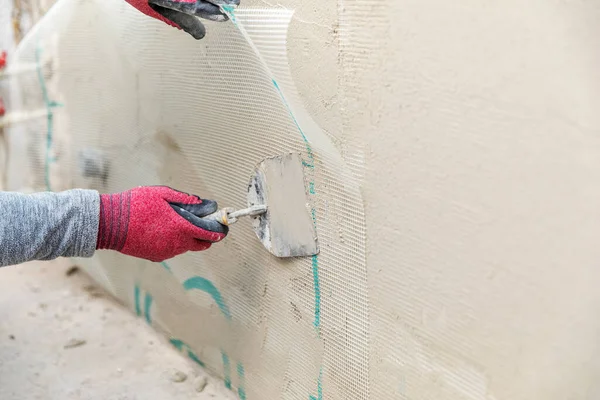 壁にガラス繊維石膏メッシュを設置する建設労働者 — ストック写真