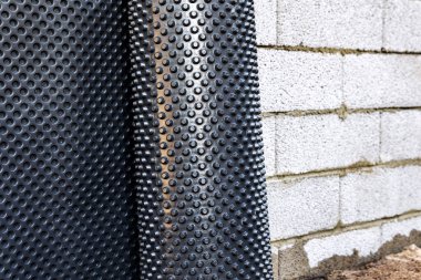 basement wall waterproofing - installing dimple geomembrane clipart