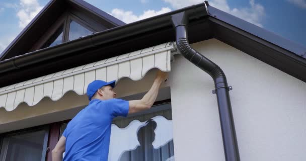 Mann Montiert Und Kontrolliert Markise Hausfassadenwand Über Balkonfenster — Stockvideo