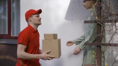 Kadın teslimatçıdan kutu teslimatını kabul ediyor.
