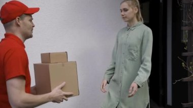 Kadın teslimatçıdan kutu teslimatını kabul ediyor.