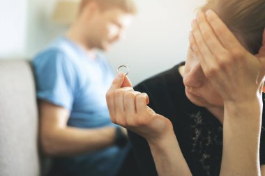 Evlilik sorunları ve çatışma konsepti. Mutsuz bir kadın elinde alyansla boşanmayı düşünüyor.