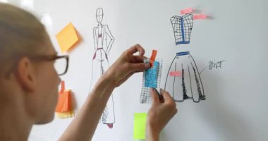 Moda tasarımcısı yeni kıyafet koleksiyonu için kumaş seçiyor.