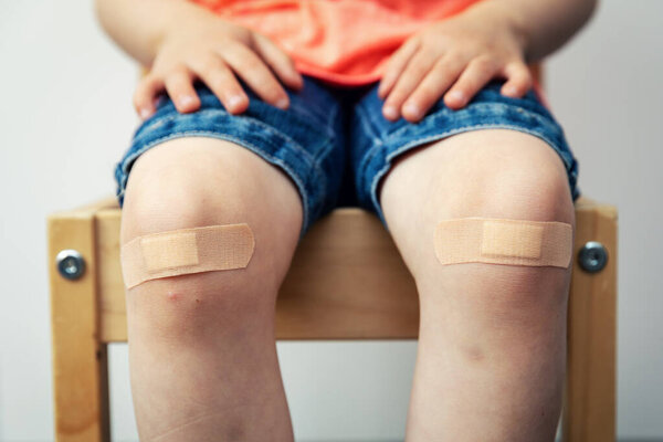 child knees with adhesive bandage strips