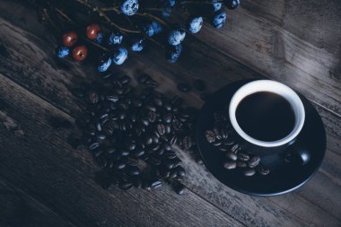 O sıcak kahve kahve çekirdekleri ve çiçeklerle siyah Kupası'nda düzenlenen