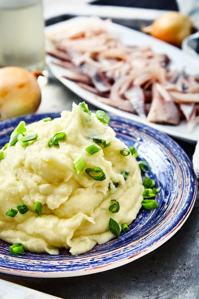 Kartoffelpüree mit Hering und eingelegten Zwiebeln Stockbild