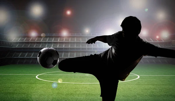 シルエットのサッカーの選手がボールを蹴る — ストック写真