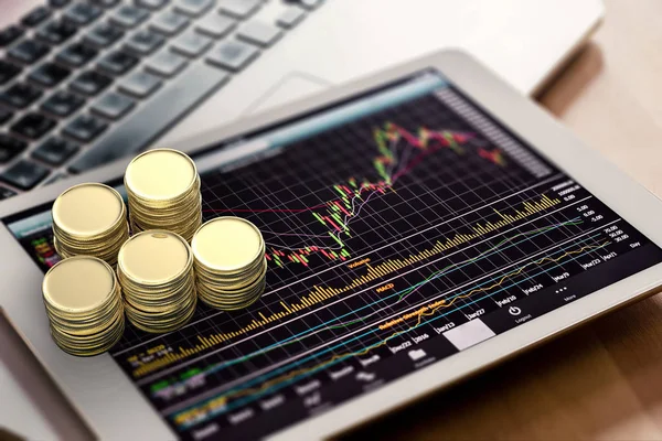 Фондовий ринок дивиться за допомогою цифрового планшета і стопки золотої монети — стокове фото