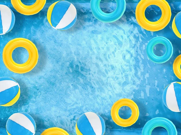 Bolas de praia e anéis de natação flutuando na piscina — Fotografia de Stock