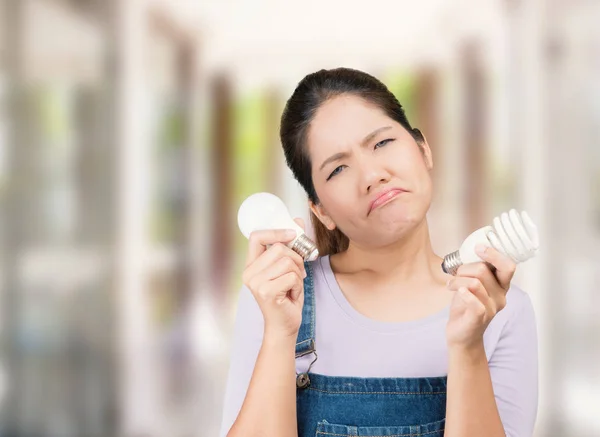 Confuso asiático mulher segurando lâmpadas — Fotografia de Stock