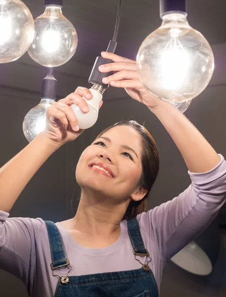 Asian woman changing light bulb — Stock Photo, Image