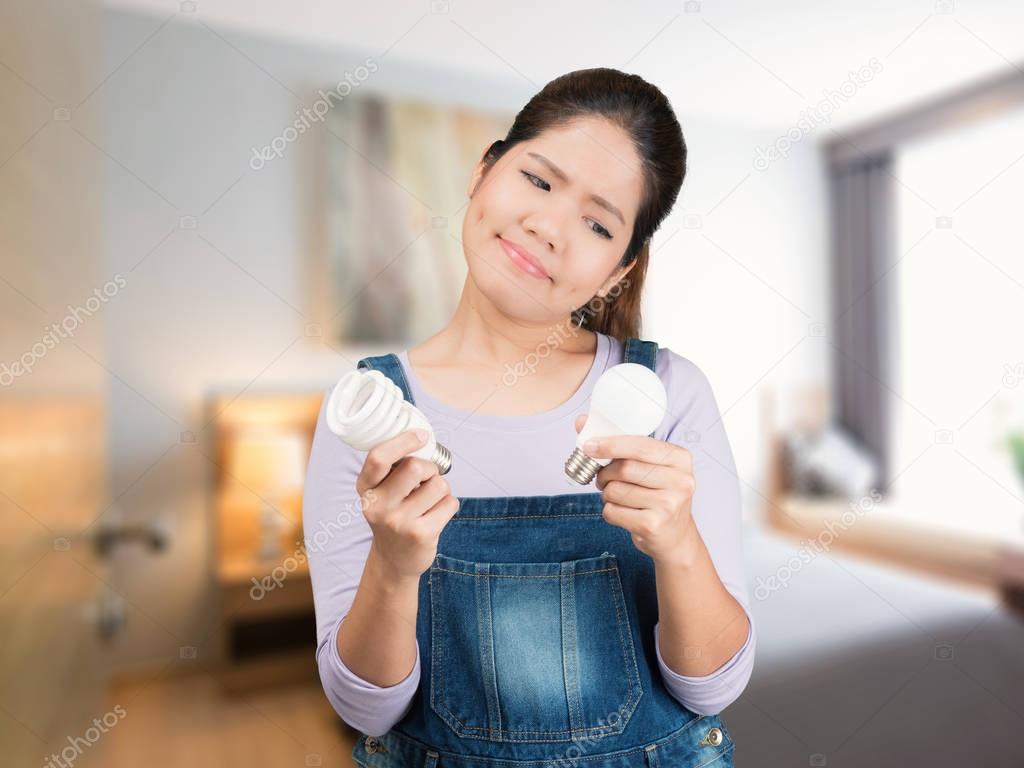 confused asian woman holding light bulbs