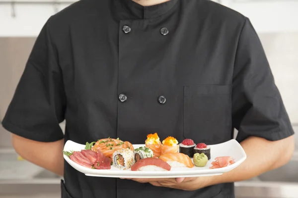 Male chef holding a plate full of sushi — Stock Photo, Image