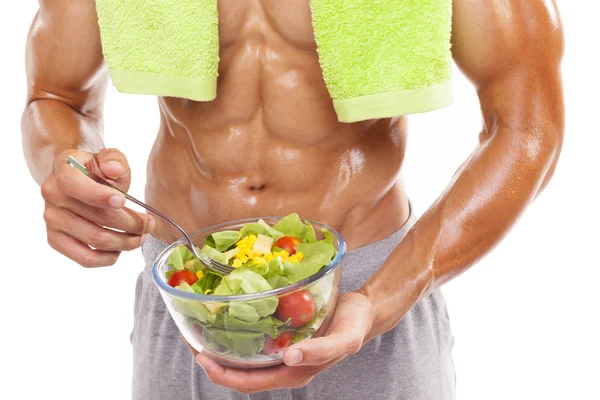 Bodybuilder håller en skål med färsk sallad på vit bakgrund — Stockfoto
