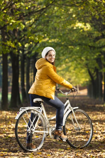 Kvinna som rider på cykel i höst park — Stockfoto