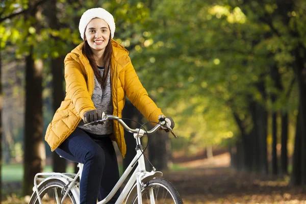 Mujer sonriente de pie en bicicleta en el parque de otoño —  Fotos de Stock