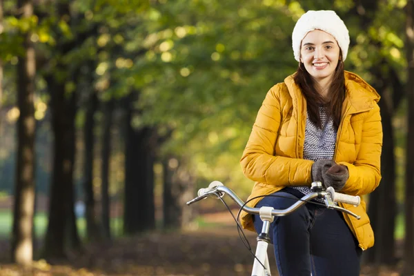 Flicka som står på cykel i höst park — Stockfoto