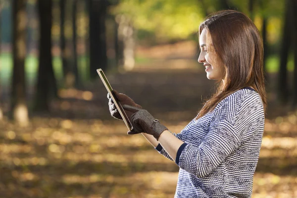 Vista laterale della donna sorridente con tablet al parco — Foto Stock