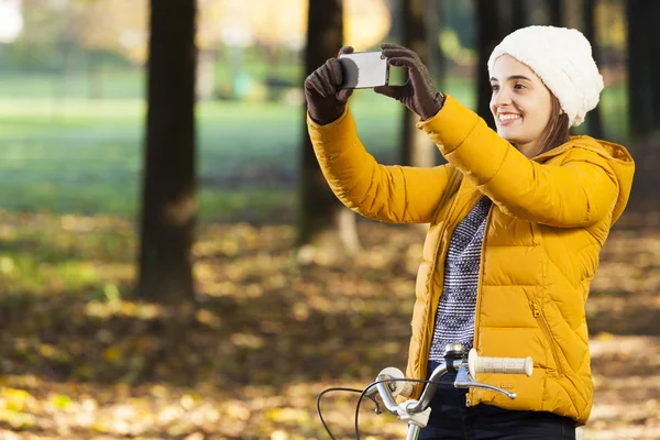 Dziewczyna na rowerze robienia zdjęć z telefonów komórkowych na zewnątrz — Zdjęcie stockowe