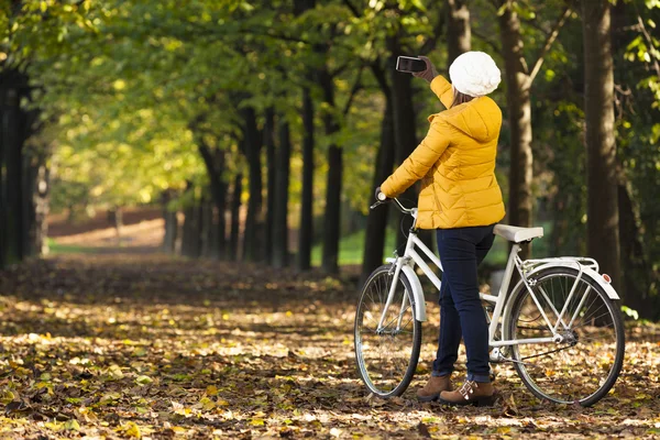 Flicka på cykel tar bilder med mobilen utomhus — Stockfoto