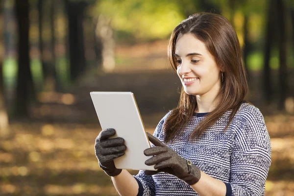 Улыбающаяся женщина с планшетным компьютером в парке — стоковое фото