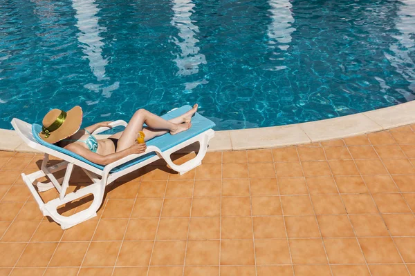 Frau entspannt sich auf Liegestühlen am Schwimmbadrand — Stockfoto