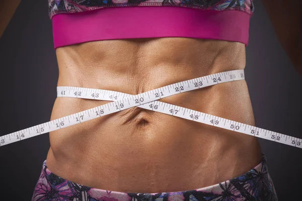 Mujer fitness midiendo su cintura por cinta métrica — Foto de Stock