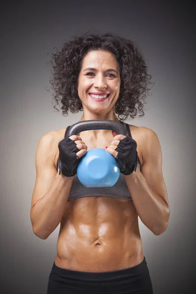 Smiling woman holding a kettle bell — Stock Photo, Image