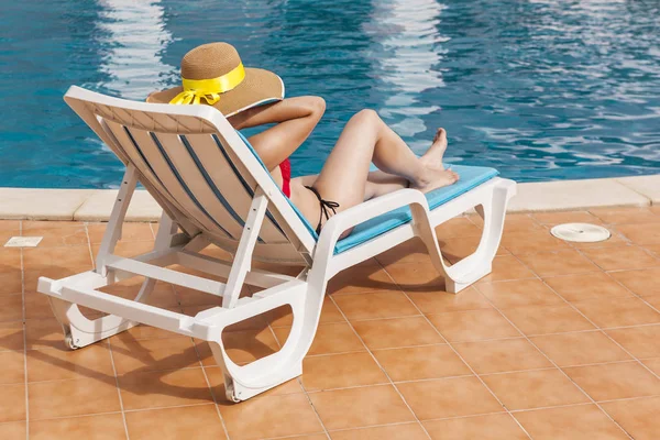 Genç kadın bir tembel, havuz kenarındaki rahatlatıcı — Stok fotoğraf