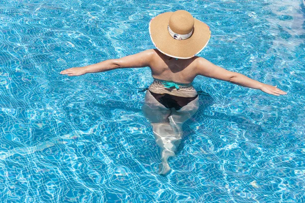 Donna in cappello godendo la piscina — Foto Stock