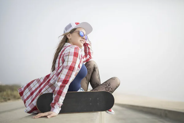 Mulher posando com um skate e olhando para o mar — Fotografia de Stock