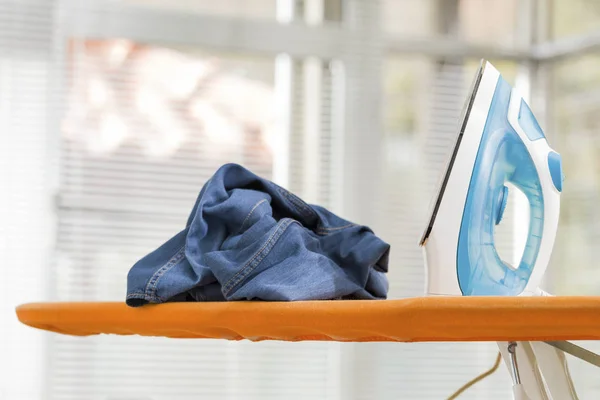 Electric iron and a wrinkled shirt on ironing board