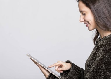 Tablet bilgisayarınızla gri arka plan üzerinde çalışan gülümseyen kadın