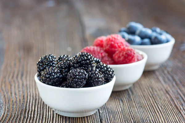 Fresh berries in bowls on a rustic wooden table — Stock Photo, Image