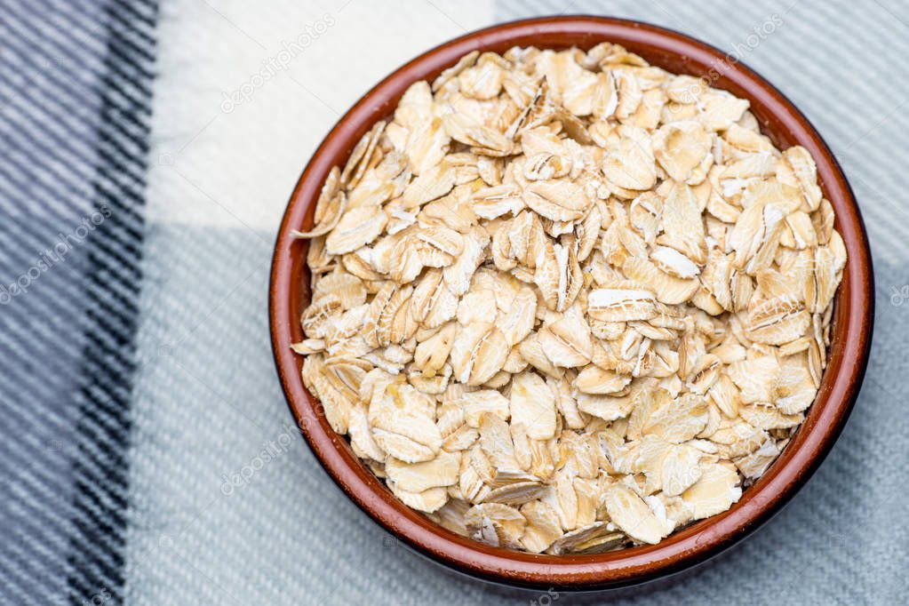 Dry rolled oat flakes oatmeal in a old bowl