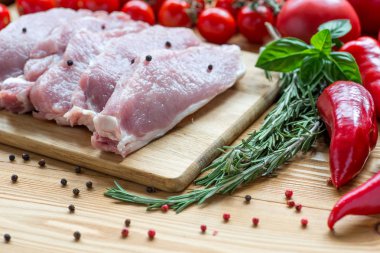 Kesme tahtasında çiğ domuz eti ve sebze.