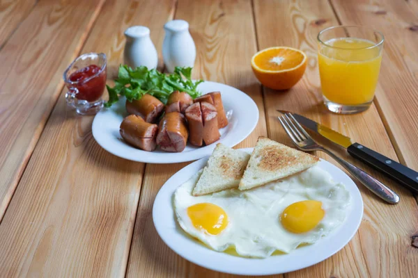 Portakal suyu, iki yumurta ve sosis sağlıklı kahvaltı için. — Stok fotoğraf