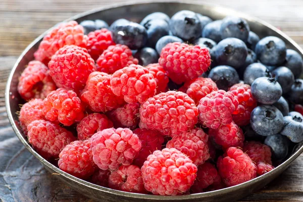 Blueberries and raspberries bowl on wooden table — Stock Photo, Image