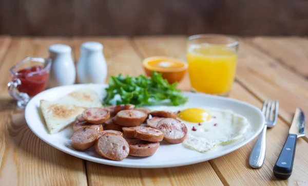 Sumo de laranja, dois ovos e salsicha para um pequeno-almoço saudável . — Fotografia de Stock