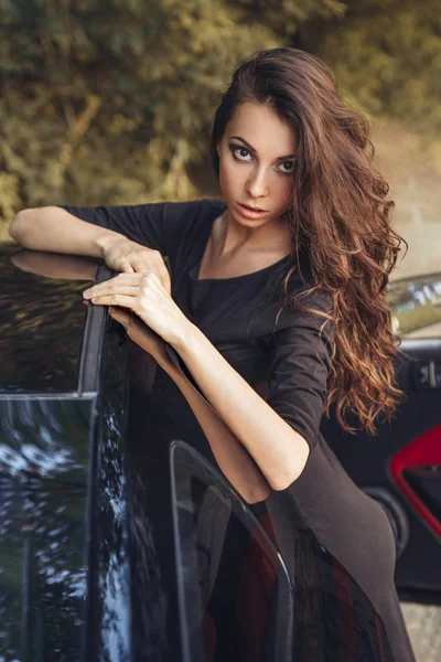 Beautiful brown hair young woman in black dress posing — Stock Photo, Image
