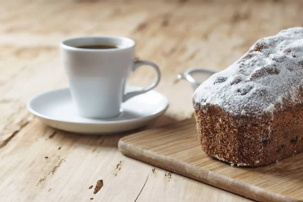Koffiekopje en cake met rozijnen op houten bureau — Stockfoto