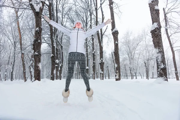 Beautiful young woman jumping the snow in winter — Stock Photo, Image