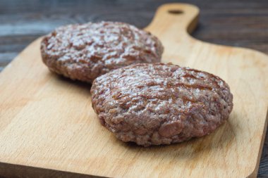 İki ızgara hamburger patty kesme tahtası üzerinde