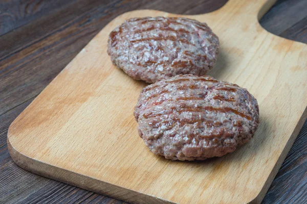 Two grilled hamburger patty on cutting board — Stock Photo, Image